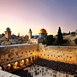 **A panoramic view of Jerusalem at sunset, showing the Western Wall (Kotel), the Dome of the Rock, and the Church of the Holy Sepulchre in the background. The style should be realistic with warm lighting.**